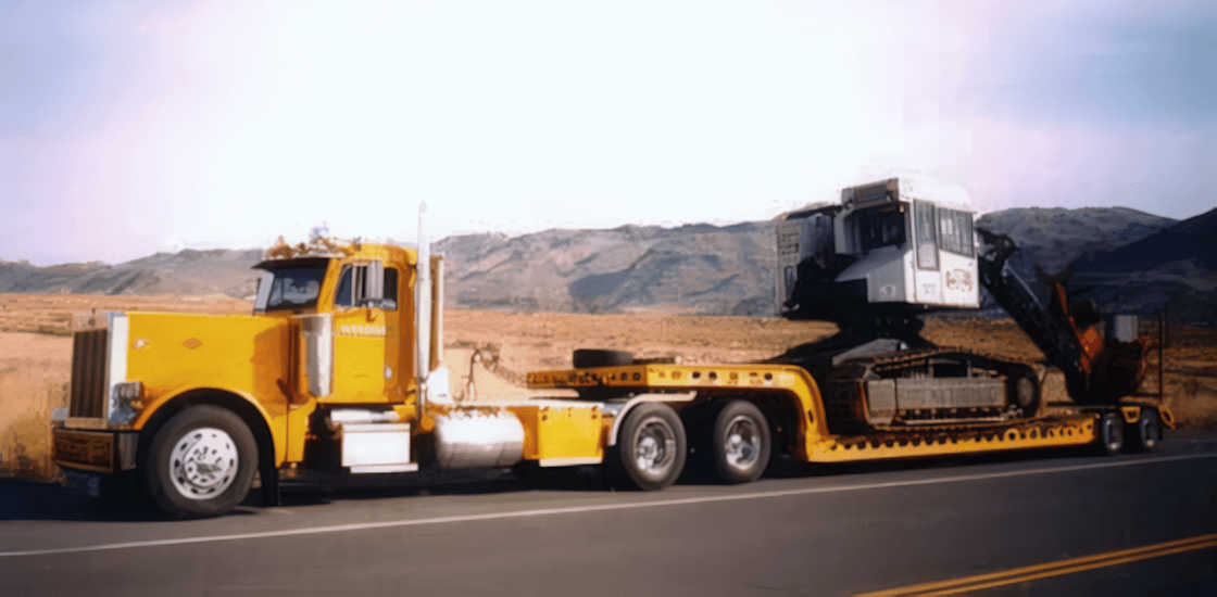 A yellow Muse Trucking truck hauling heavy machinery