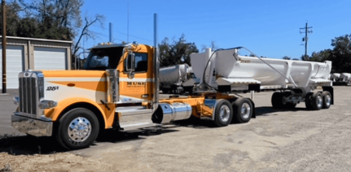 A yellow and white Muse Trucking truck ready to haul