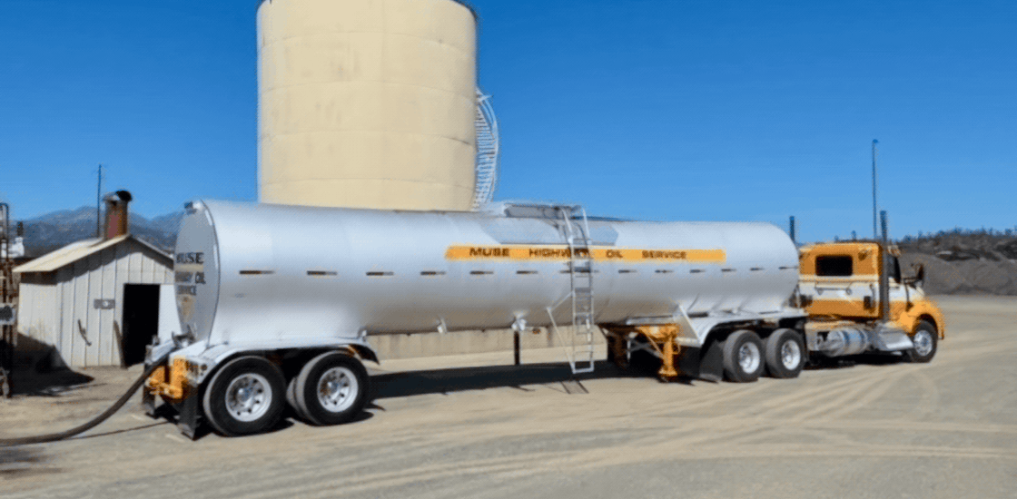 A yellow Muse Trucking truck hauling an oil tank